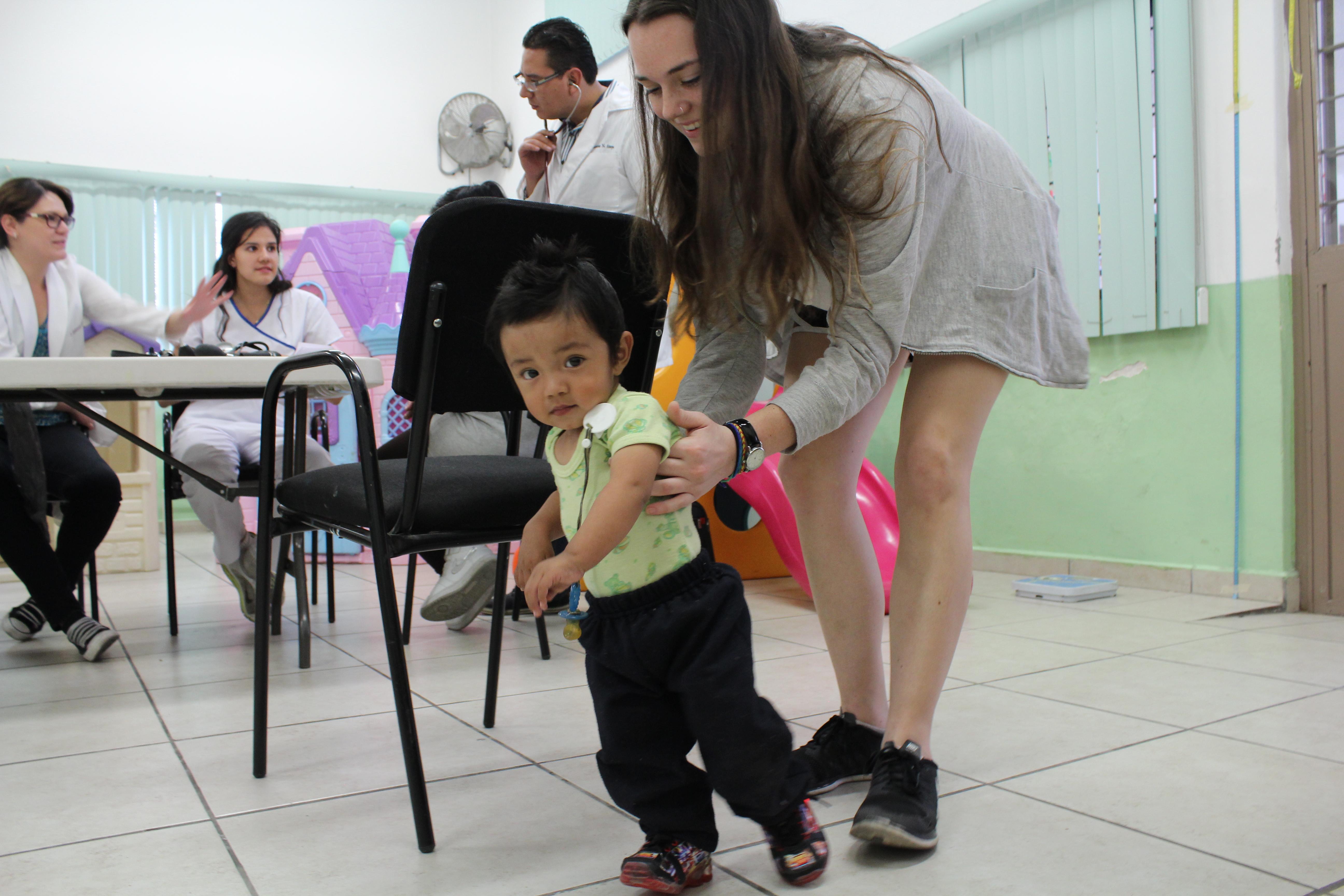 Female intern with Projects Abroad helping a child learn to walk as part of her physiotherapy internship in Mexico. A female intern with Projects Abroad is pictured helping a child learn to walk as part of her physiotherapy internship in Mexico.
